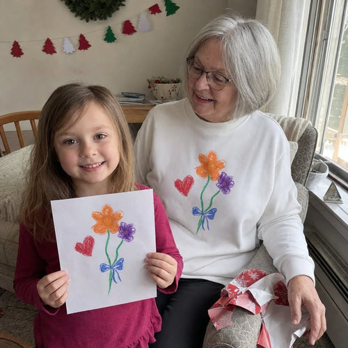 Grandma in a white sweatshirt printed with a kid's flower drawing, next to the paper original