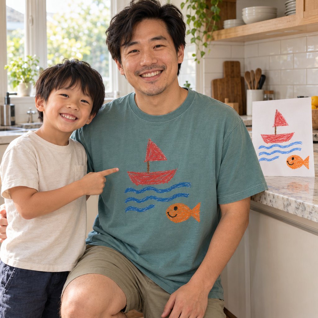 Dad in a seafoam premium tee printed with his son's sailboat drawing, next to the paper original
