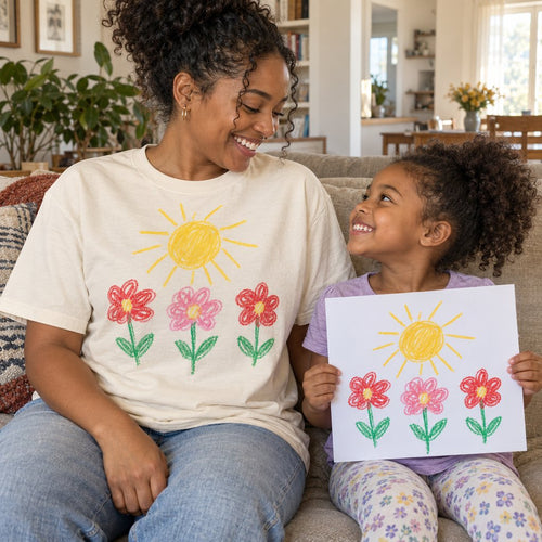 Mom in an ivory premium tee printed with her daughter's flower drawing, next to the paper original