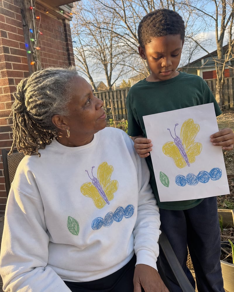 Grandma in a white sweatshirt printed with a kid's butterfly drawing, next to the paper original